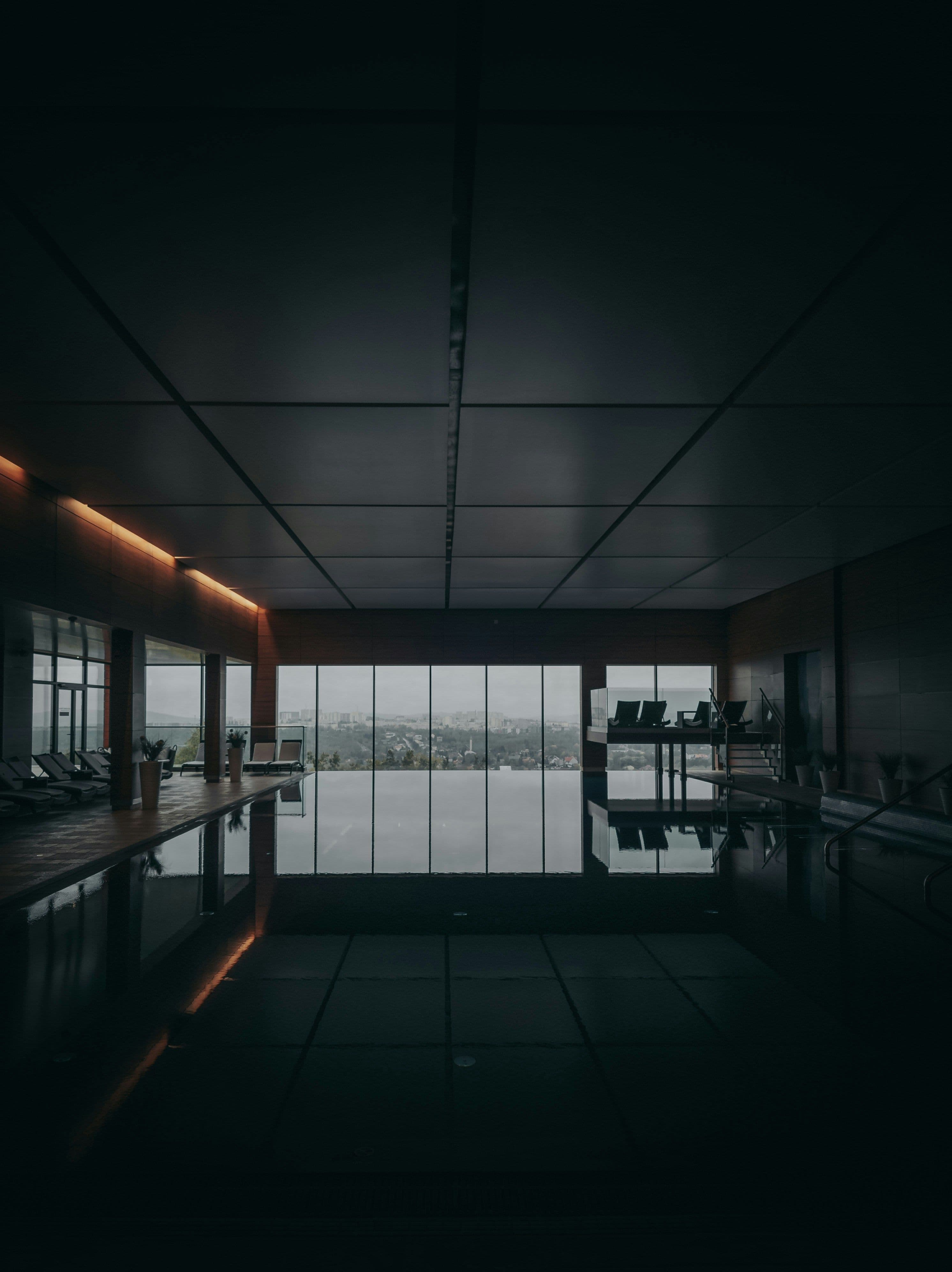 Piscine d'hôtel parisien en marbre, baies vitrées au crépuscule, lumière feutrée typique des spas 4 et 5 étoiles ouverts à la journée